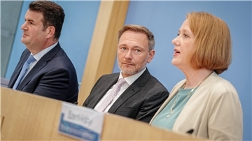 Zwei Männer und eine Frau sitzen in der Bundes-Pressekonferenz