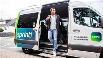 Ein Mann steigt aus einem Kleinbus mit der Aufschrift "sprinti"