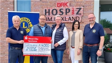 Vor einem Eingang mit dem Schriftzug "DRK Hospiz im Cuxland" stehen zwei Frauen und drei Männer nebeneinander. Zwei von ihnen halten einen symbolischen Spendenscheck über 4000 Euro.