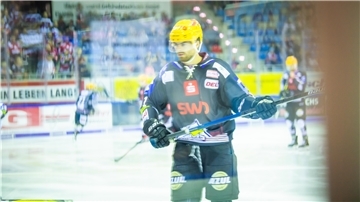 Eishockeyspieler nimmt Schläger in beide Hände.