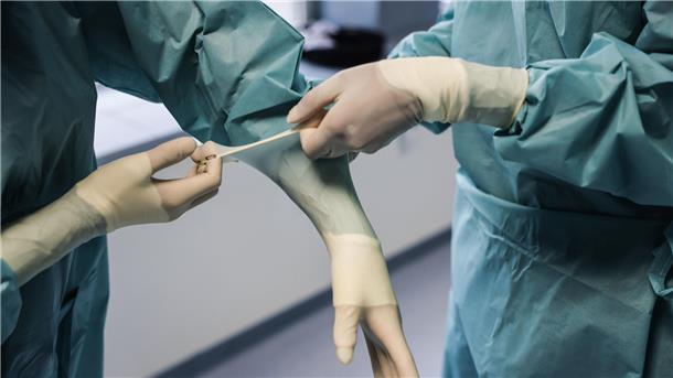 NZ-Kommentar zu Behandlungsfehlern: Patienten können Vertrauen haben Ärzte ziehen OP-Handschuhe an.