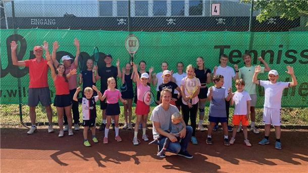 Eine große Gruppe von Kindern und Jugendlichen mit ihren erwachsenen Trainern hält jubelnd die Hände hoch