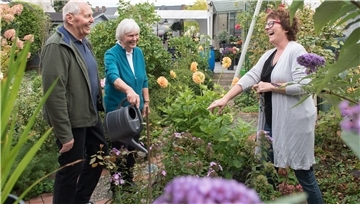 Ein Mann unterhält sich mit zwei Frauen in einem Garten