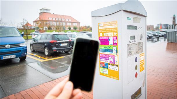Ein Handy vor einem Parkscheinautomaten