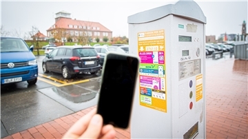 Ein Handy vor einem Parkscheinautomaten