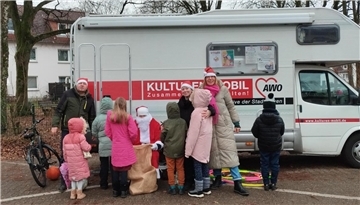 Einige Kinder versammeln sich um den Nikolaus vor dem Kulturen-Mobil.