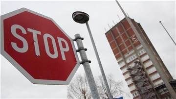 Das Foto zeigt ein Stopschild, eine Straßenlaterne und den Rathausturm in Nordenham.