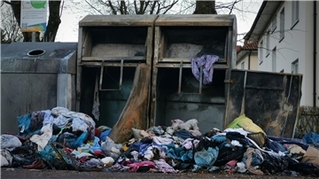 Das Foto zeigt zwei ausgebrannte Altkleider-Container. Davor liegen Wäscheberge.
