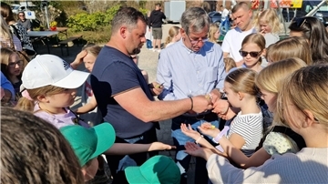 Zwei Männer verteilen Freifahrtchips an Kinder.