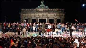 Jubelnde Menschen auf der Berliner Mauer am Brandenburger Tor. 