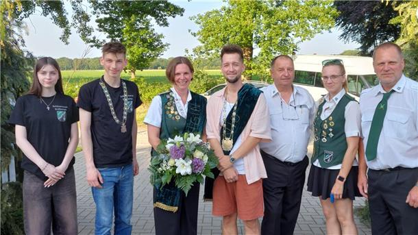 Gruppenfoto von sieben Mitgliedern des Schützenvereins Großenhain. Zwei Jugendliche tragen schwarze Vereins-T-Shirts, die anderen sind teils in Uniform mit grünen Schärpen oder Westen gekleidet. Eine Frau hält einen Blumenstrauß.