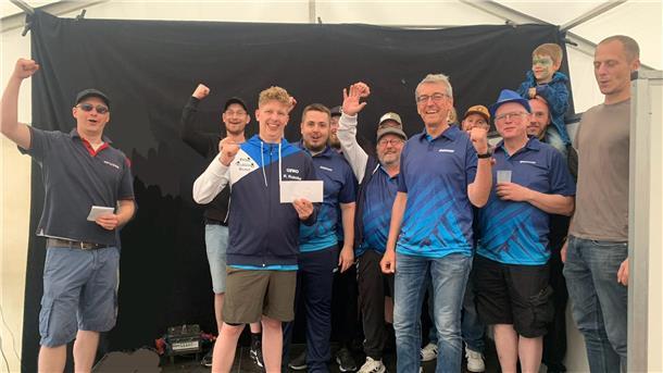 „Tischtennis-Freaks“ siegen beim Dorffest Geestenseth Gruppe jubelnder Männer, teils in blauen Sporttrikots, steht vor schwarzem Hintergrund in einem Festzelt. Zwei Personen halten Umschläge, ein Kind mit Gesichtsbemalung sitzt auf den Schultern.