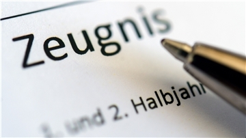 Ein Kugelschreiber wird über Zeugnis gehalten.