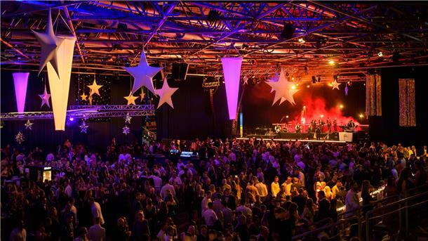 Hunderte Menschen tanzen in der festlich geschmückten Stadthalle.