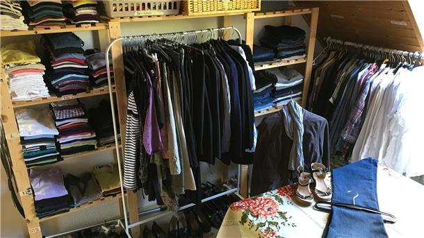 Dachgeschossraum mit Regalen und Stangen voller Kleidung