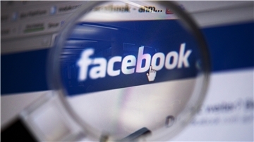 Blick durch eine Lupe auf das Logo des sozialen Netzwerkes Facebook.
