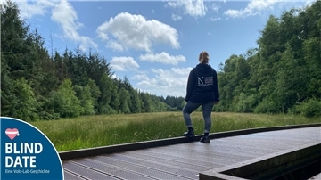 Eine Frau steht auf einem Steg und schaut über das Moor