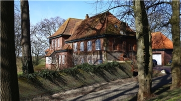 Blick vom Friesenhügel auf das Steinhaus in Langwarden. Es soll aus Steinen der Olde Kerke gebaut worden sein und ist das älteste Haus Butjadingens. Der Graue Tuffstein wurde extra aus der Eifel geholt. Viele Fenster sind später verschlossen worden.