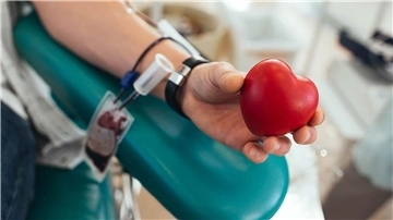 Blutspende einer Person, die ein rotes Herz (vermutlich aus Holz) in den Händen hält. Blutspenden rettet Leben – eine einzige Spende kann bis zu drei Menschen helfen. Am 29. Juli lädt das St. Bernhard Hospital Brake zur Aktion ein.