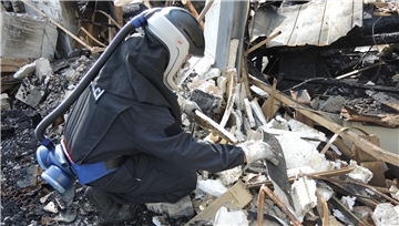  Brandursachenermittler Stephan W. sucht nach dem Feuer in Bramstedt nach Spuren in Trümmern. Ein Helm mit Luftfilter schützt ihn vor schädlichen Dämpfen.