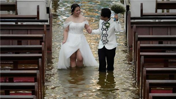 Heiraten mit pitschnassen Füßen Braut und Bräutigam waten durch die überflutete Kirche auf den Philippinen.