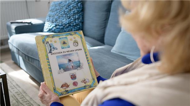In Bremerhaven verwurzelt: Diamantenes Hochzeitspaar reist aus den USA an Eine Frau hält ein Fotobuch in der Hand.