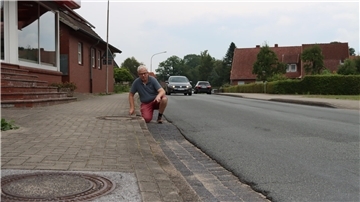 Bürgermeister Frank Tibke moniert den schlechten Zustand der Kirchtimker Ortsdurchfahrt. Für die Anwohner bedeutet die marode Straße viel Lärm.