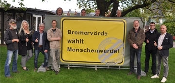 Bürgermeister und Ortsvorsteher der Stadt Bremervörde sowie Aktive des Bündnisses für Demokratie und Menschenwürde stellen das Banner vor, das ab nächsten Dienstag in jeder der zwölf Bremervörder Ortschaften stehen wird.