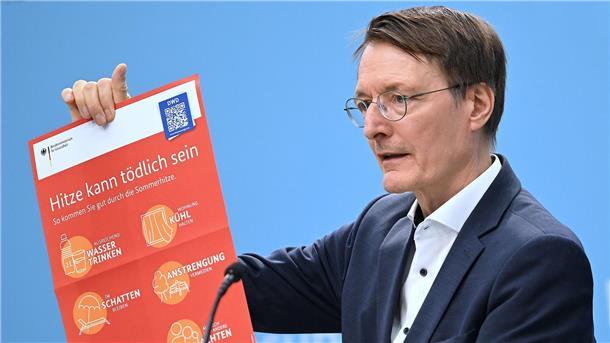 Bundesgesundheitsminister Karl Lauterbach (SPD) hält ein Plakat zum Thema Hitzeschutz hoch.