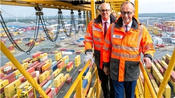 Bundeskanzler Friedrich Merz (CDU, vorn) und Andreas Bovenschulte (SPD), Bremer Landeschef, stehen auf einer Containerbrücke an der Stromkaje im Überseehafen Bremerhaven. 