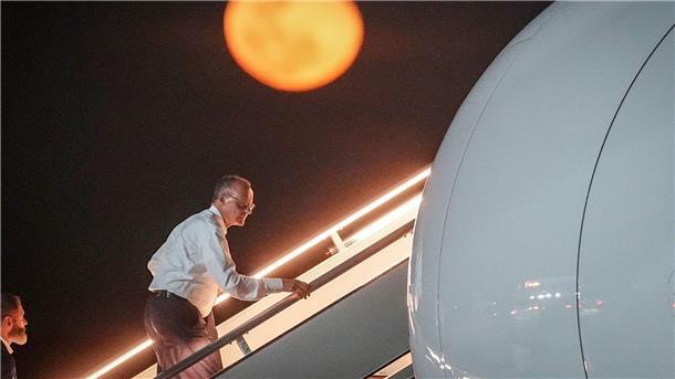 Bundeskanzler Friedrich Merz geht die Gangway vor dem aufgehenden Mond hinauf.