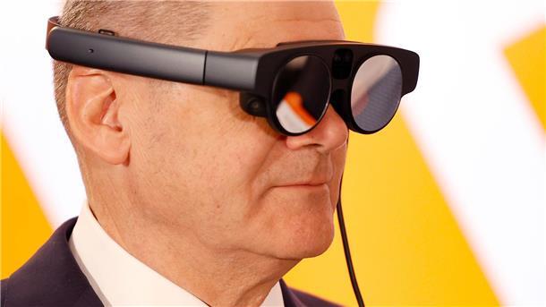 Bundeskanzler Olaf Scholz mit eier AR-Datenbrille (Augmented Reality) zur Prozessüberwachung einer Maschine.