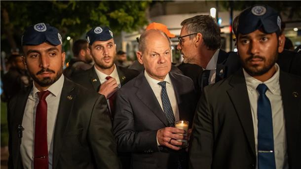Raketen-Alarm in Tel Aviv: Kanzler-Flieger geräumt Bundeskanzler Olaf Scholz, umringt von Bodyguards, bei seinem Solidaritätsbesuch in Israel mit einer Kerze in der Hand am Dizengoff Square im Zentrum von Tel Aviv.