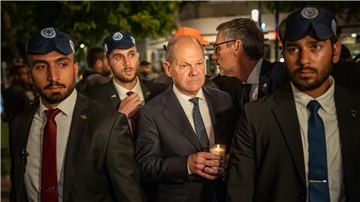 Bundeskanzler Olaf Scholz, umringt von Bodyguards, bei seinem Solidaritätsbesuch in Israel mit einer Kerze in der Hand am Dizengoff Square im Zentrum von Tel Aviv.