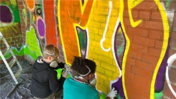 Bunt statt trist: Kinder vom Tarmstedter Jugendtreff sprayen Graffiti-Kunstwerke an die Wände des Bushäuschens. 