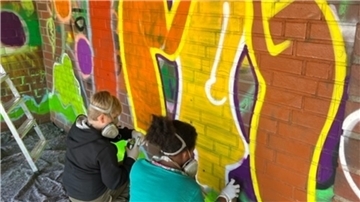 Bunt statt trist: Kinder vom Tarmstedter Jugendtreff sprayen Graffiti-Kunstwerke an die Wände des Bushäuschens. 