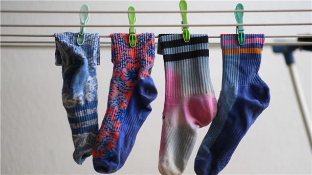 Kann die Waschmaschine Socken fressen? Bunte Socken hängen auf einem Wäscheständer. Am 9. Mai ist Tag der verschwundenen Socken.