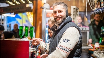 Mann mit Weste zapft Glühwein