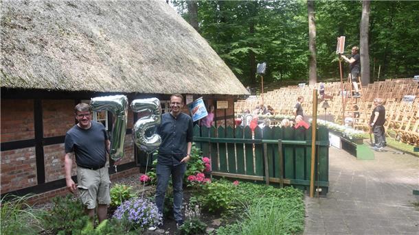 Zwei Männer stehen neben Folienluftballons mit den Ziffern 7 und 5.