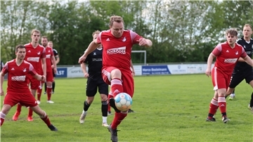 Mehrere Männer in roten Trikots und einer hat den Ball am Fuß.