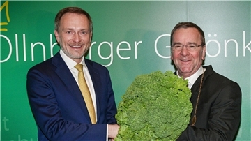 Christian Lindner (l) übergibt dem neuen Oldenburger Grünkohlkönig Boris Pistorius mit einer Grünkohlpflanze sein Ehrenamt.