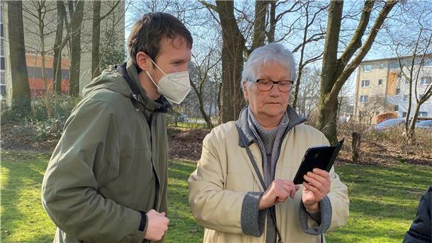 Christian Sanders erklärt Rita Lehm die Funktion ihres Mobiltelefons.