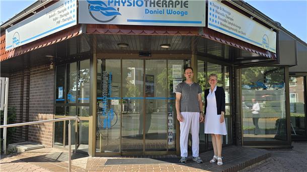 Christiane Thürlings, Vorstand der Raiffeisenbank, und Physiotherapeut Daniel Wooge stehen vor dem Praxisgebäude. 