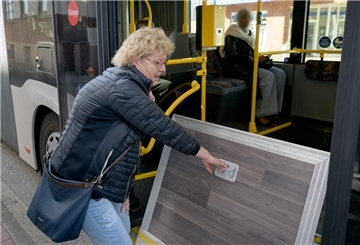 Eine Frau klappt eine Rampe runter. Sie steht an einem Bus.