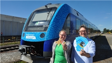 Christoph Nagel und Lena Kaplan von der Unternehmenskommunikation der EVB weisen auf die historischen Fahrkarten hin, die für Sonderfahrten zum Bahnhofsfest erhältlich sind. 