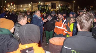 Claus Seebeck (blaue Jacke) spricht zu den Landwirten.