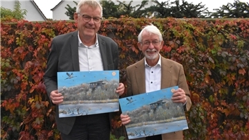 Zwei ältere Männer halten jeweils ein Bild in der Hand.