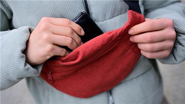 Ripp-Chic für „Drinnies“? Warum es ein Cord-Comeback gibt Cord lässt sich im Alltag wieder öfter antreffen; Eine Frau trägt eine Jacke und eine Brusttasche aus Cord und steckt ihr Portemonnaie in die Tasche. (Foto: Illustration)