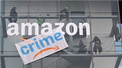 "Crime" statt Prime: Greenpeace-Aktivisten hängen während des Black Fridays 2022 ein Transparent mit der Aufschrift «crime» an der Zentrale von Amazon Deutschland in München auf. Amazon steht immer wieder in der Kritik. Darauf reagiert der Konzern mit Image-Werbung.