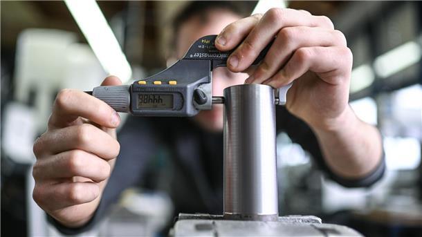 zwei Hände umfassen ein Metallwerkstück